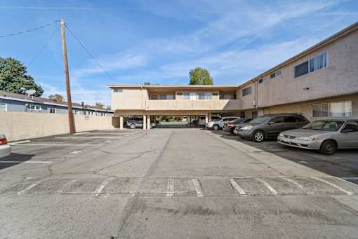 A parking lot with a building in the background and several cars parked.