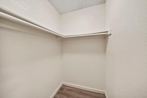 A white closet with a shelf and a wooden floor.