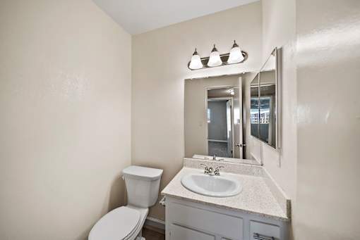 A bathroom with a toilet, sink, and mirror.