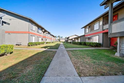 A long concrete walkway separates two rows of identical houses.