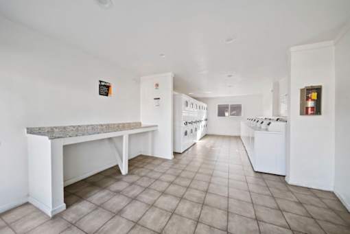 A kitchen with white appliances and a marble island.