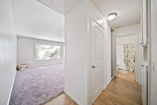A hallway with a purple carpet and white walls.