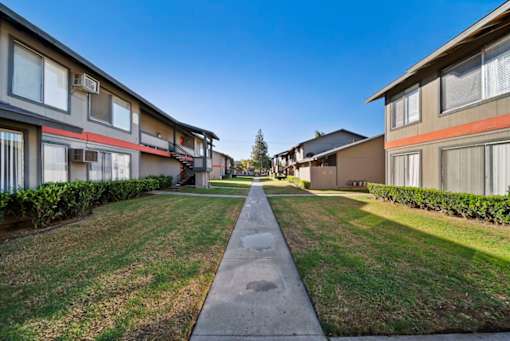 A long concrete walkway separates two rows of houses.