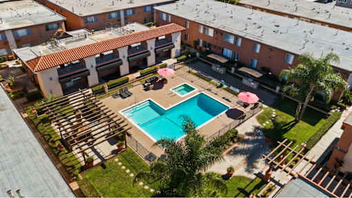 A swimming pool surrounded by a patio with chairs and umbrellas.