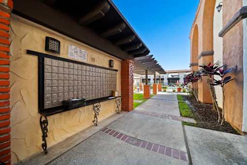 A long, narrow walkway with a brick wall and a metal gate.