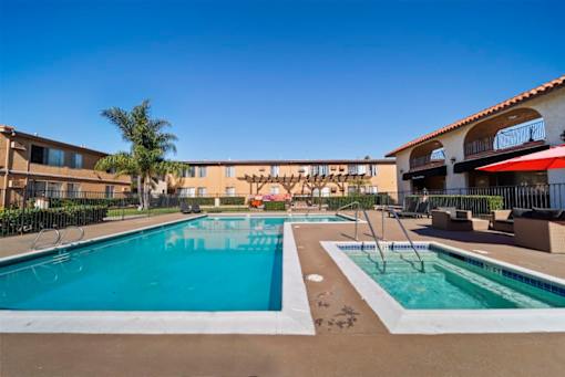A large outdoor swimming pool with a slide and a smaller pool with a fountain.