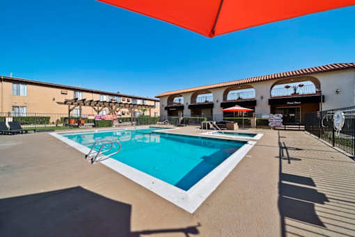 A large swimming pool with a red umbrella above it.