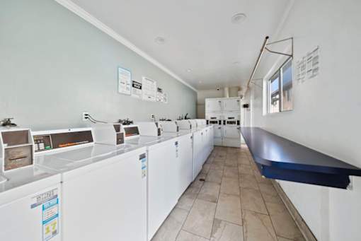 A laundromat with a row of washers and dryers.