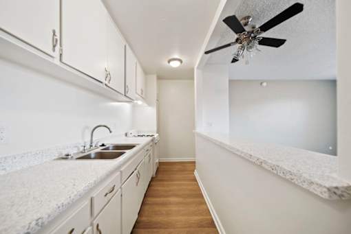 A kitchen with white cabinets and a marble countertop.