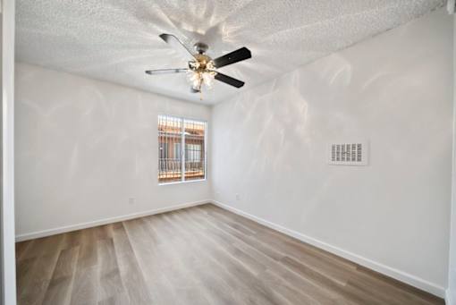 A room with a ceiling fan and a window with bars.
