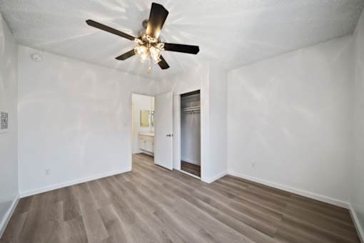 A room with a ceiling fan and wooden flooring.