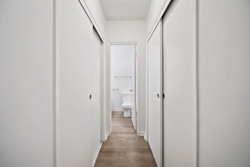 A long hallway with a toilet at the end.