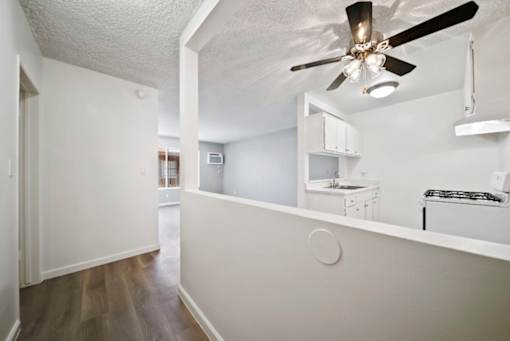 A white room with a ceiling fan and a small kitchenette.