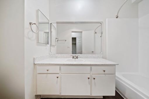 A white bathroom with a sink and a mirror.