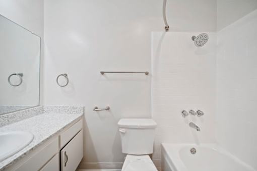 A white bathroom with a toilet, sink, and bathtub.
