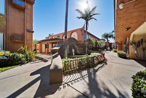 A sunny day in a residential area with a street leading to a house.