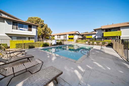 A pool surrounded by a fence and chairs.