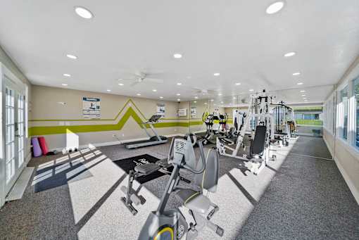 A gym with a variety of equipment including treadmills, weights, and exercise machines.