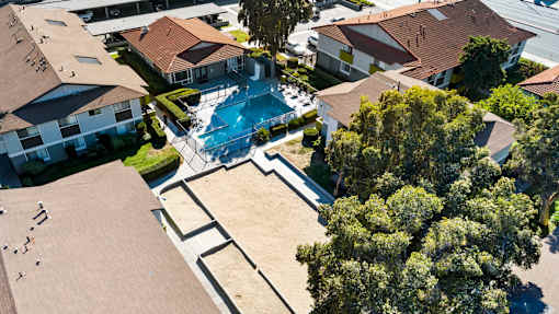 A bird's eye view of a residential area with houses, a swimming pool, and trees.