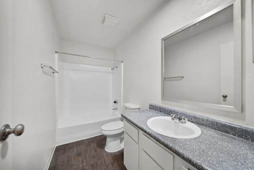 A bathroom with a toilet, sink, and mirror.