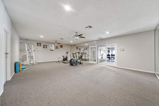 A spacious room with a ceiling fan and exercise equipment.