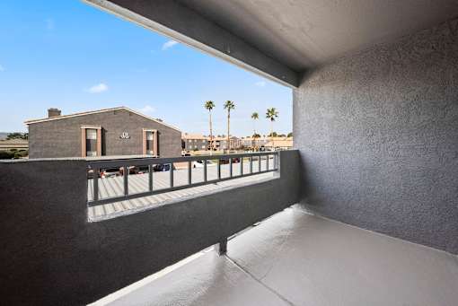 A balcony with a railing overlooks a building and palm trees.