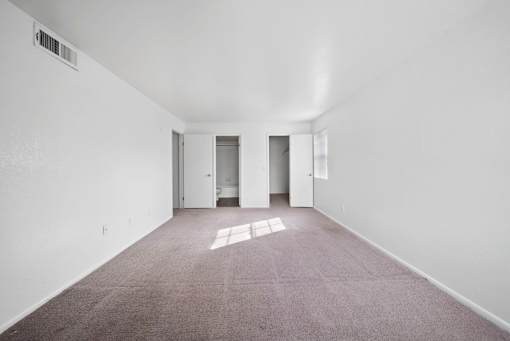 A large empty room with carpeted floor and white walls.