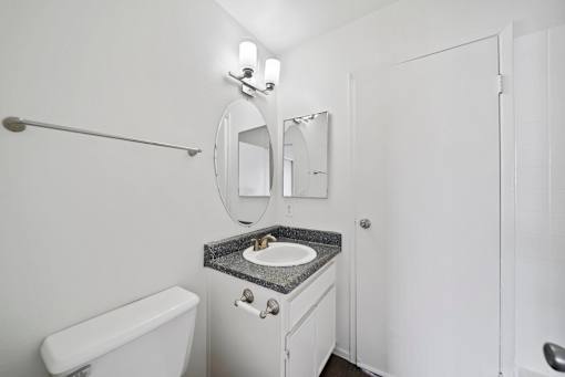 A white bathroom with a sink, toilet, and mirror.
