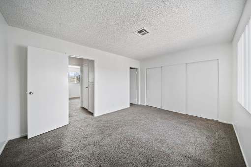 A spacious room with white walls and carpeted floor.