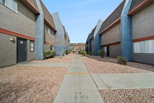 A long concrete walkway separates apartment buildings.