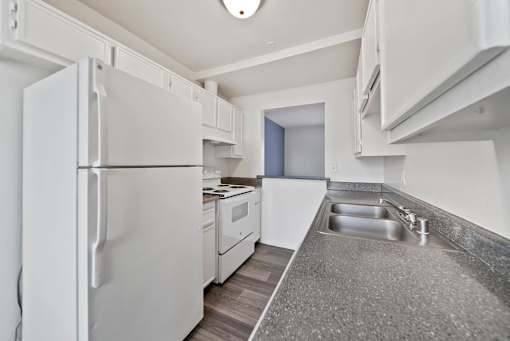 A white refrigerator is in a kitchen with a sink and a counter.