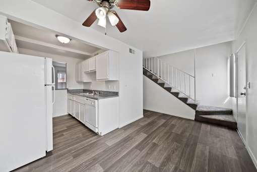 A kitchen with white appliances and a staircase.