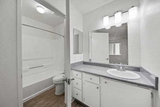 A bathroom with a toilet, sink, and mirror.