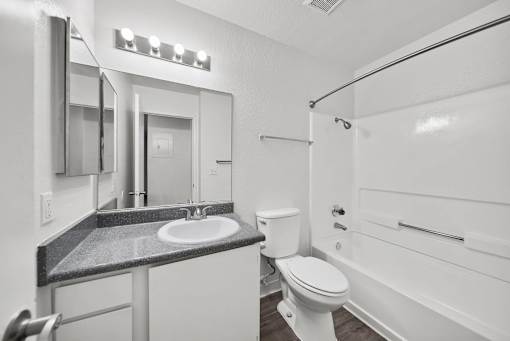 A bathroom with a toilet, sink, and mirror.