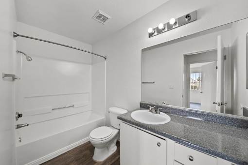 A white bathroom with a toilet, sink, and mirror.