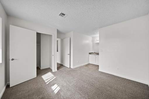 A white room with a carpeted floor and a white door.