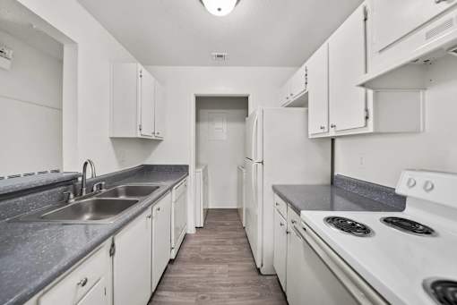 A kitchen with white cabinets and a stove top oven.
