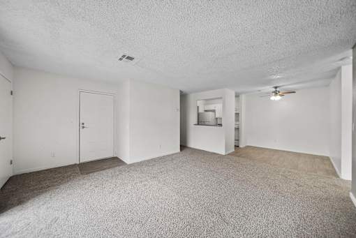 A spacious room with a carpeted floor and a ceiling fan.