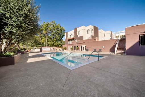 A pool in a courtyard surrounded by trees and buildings.