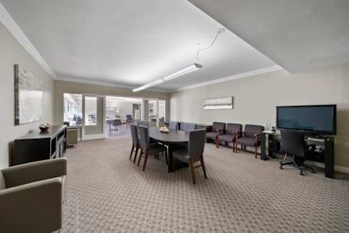 A room with a grey carpet and a black television.