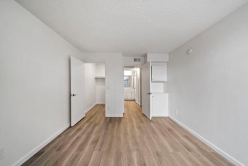 A long hallway with white walls and wood flooring.