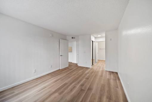 A long hallway with white walls and wood flooring.