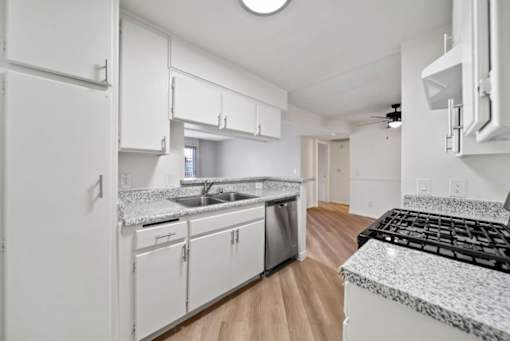 A kitchen with white cabinets and a granite countertop.
