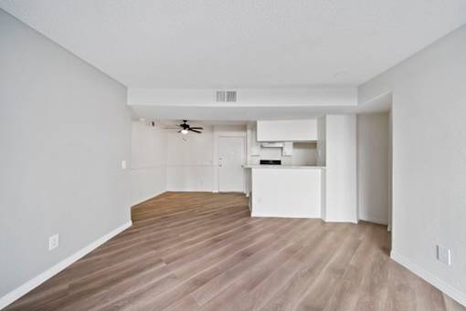 A room with a ceiling fan and a kitchenette.