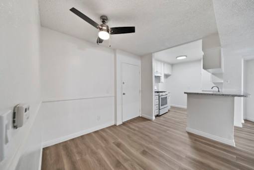 A kitchen with a ceiling fan and wooden floors.