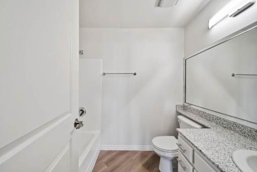 A white bathroom with a toilet, sink, and mirror.