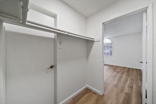 A white door with a black handle is in a room with white walls and wood flooring.