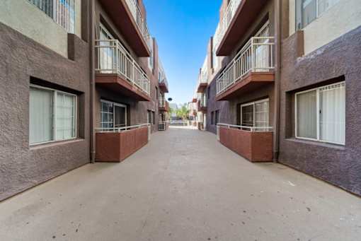 A long, narrow alleyway between two buildings with balconies.