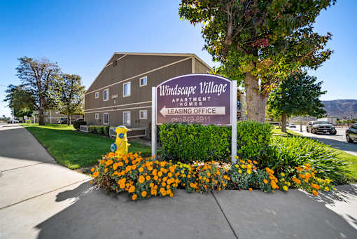 A sign for Windsafe Village Apartment is in front of a building.