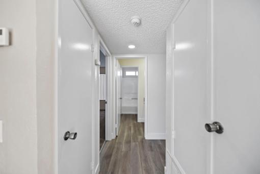 A long hallway with white walls and a wooden floor.